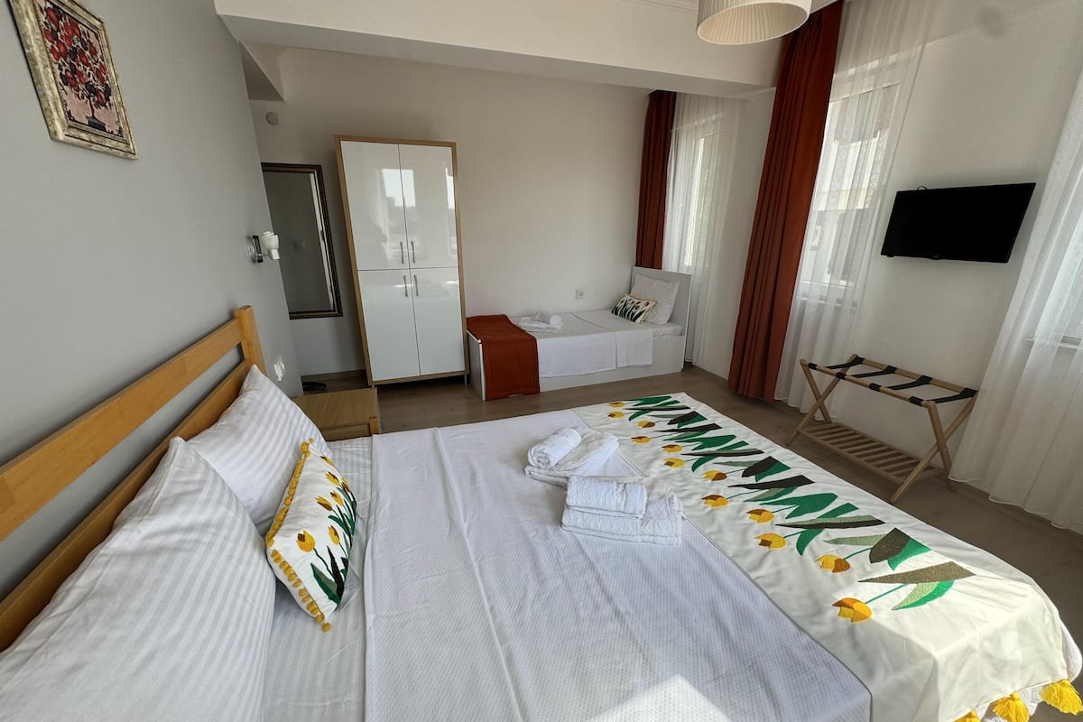 Una habitación de hotel con una cama, un armario, un televisor y una ventana con cortinas.