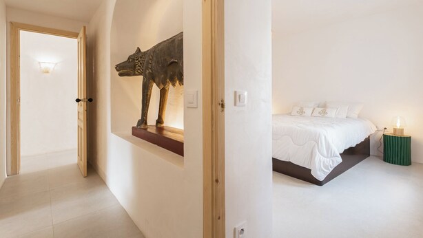 A bedroom with a bed, a wall-mounted sculpture, and a bedside lamp. - Typical  ibiza-style family villa with large swimming pool 15 mn from Sitges (Cunit)