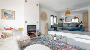 A living room with a glass coffee table, a sofa, a fireplace, and a TV. - Typical  ibiza-style family villa with large swimming pool 15 mn from Sitges (Cunit)