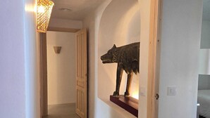 A hallway with a wooden door frame, a wall-mounted sculpture of a wolf, and a light fixture. - Typical  ibiza-style family villa with large swimming pool 15 mn from Sitges (Cunit)