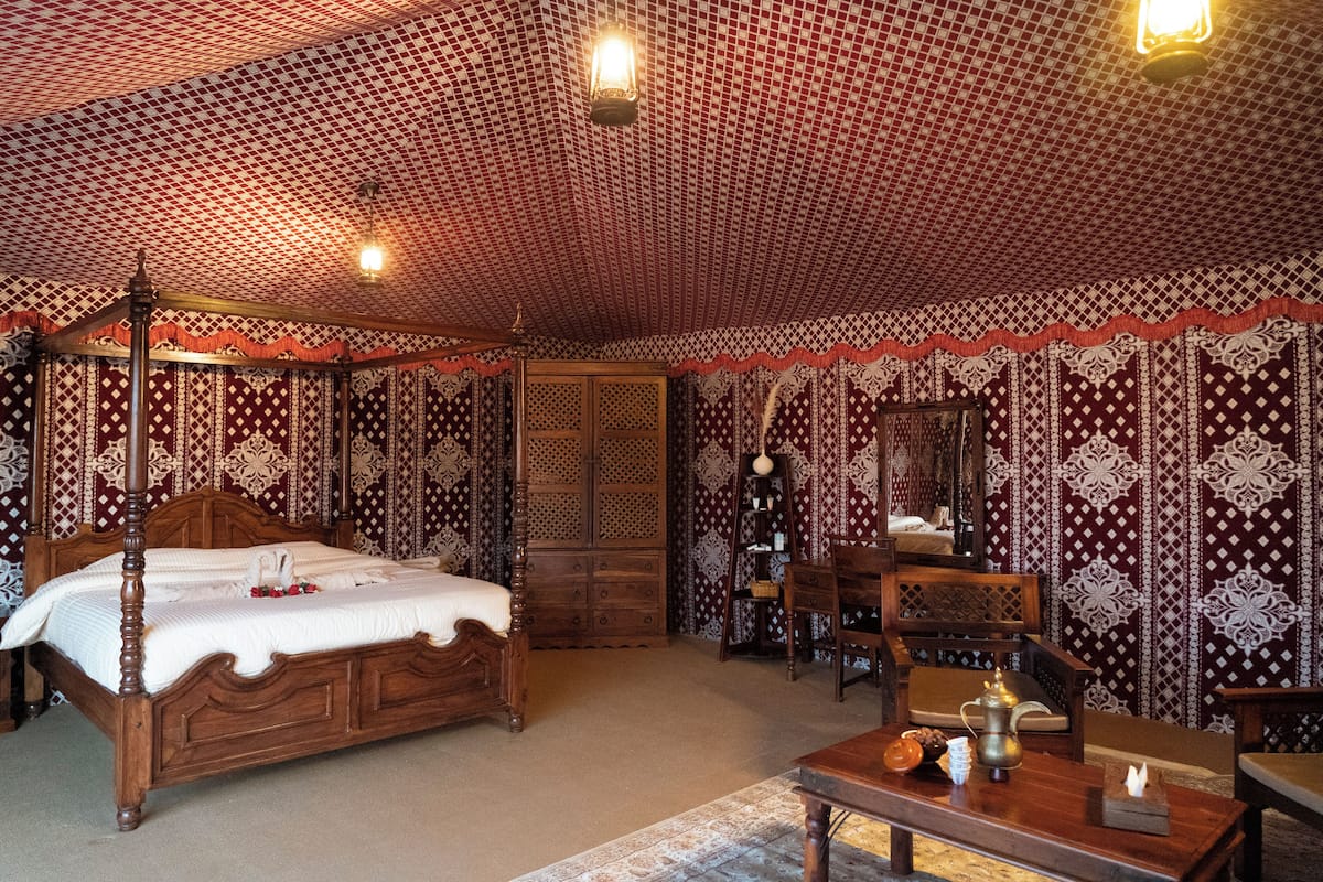 Une chambre de style traditionnel, dotée d’un lit à baldaquin, d’un bureau en bois et d’un papier peint à motifs.