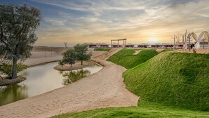 Un área ajardinada con un sendero, un estanque y un edificio de diseño moderno.