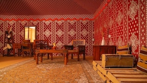 Una habitación tradicional con paredes de madera con patrón rojo y blanco, una mesa de madera, sillas y un sofá.