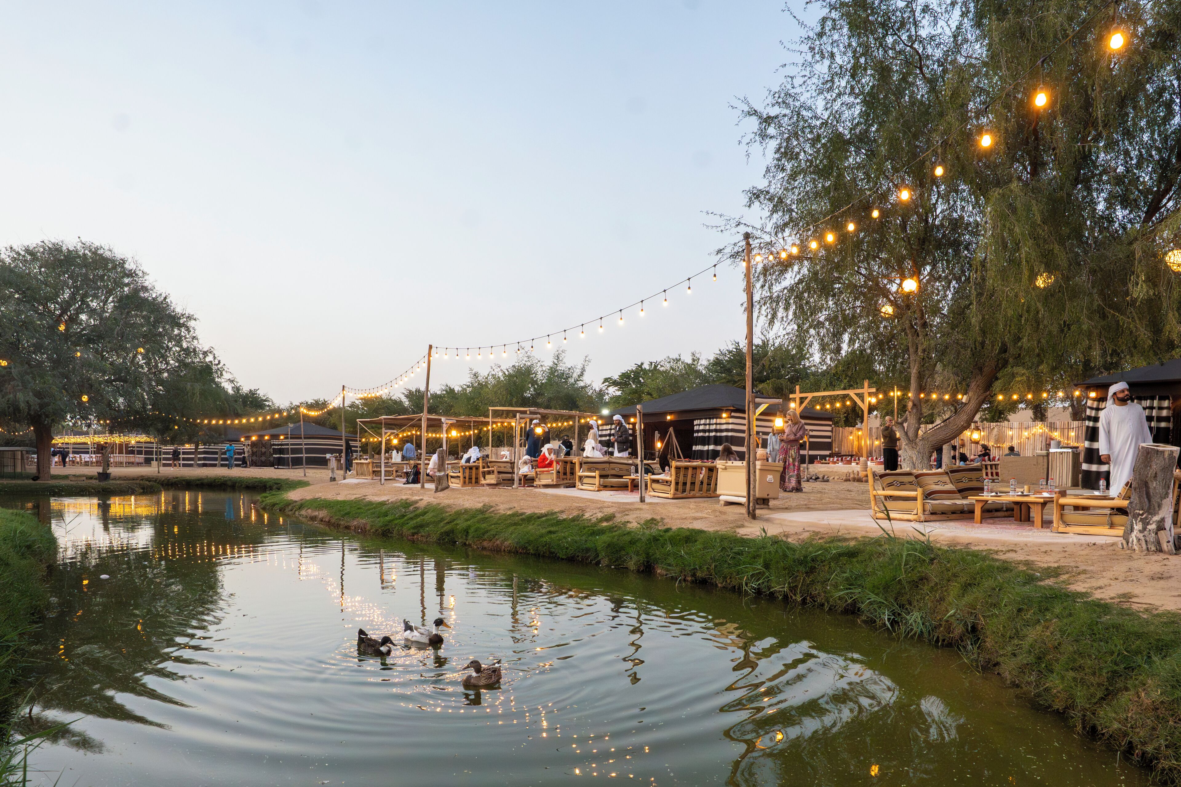 A riverside outdoor area with seating and string lights.
