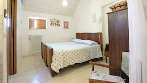 Ein Schlafzimmer mit Bett, Holz-Kopfteil, einem Fenster, einer Heizung und einem Holzschrank.