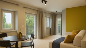 Una sala de estar moderna con un sofá, una mesa de comedor con sillas y ventanas grandes con cortinas.