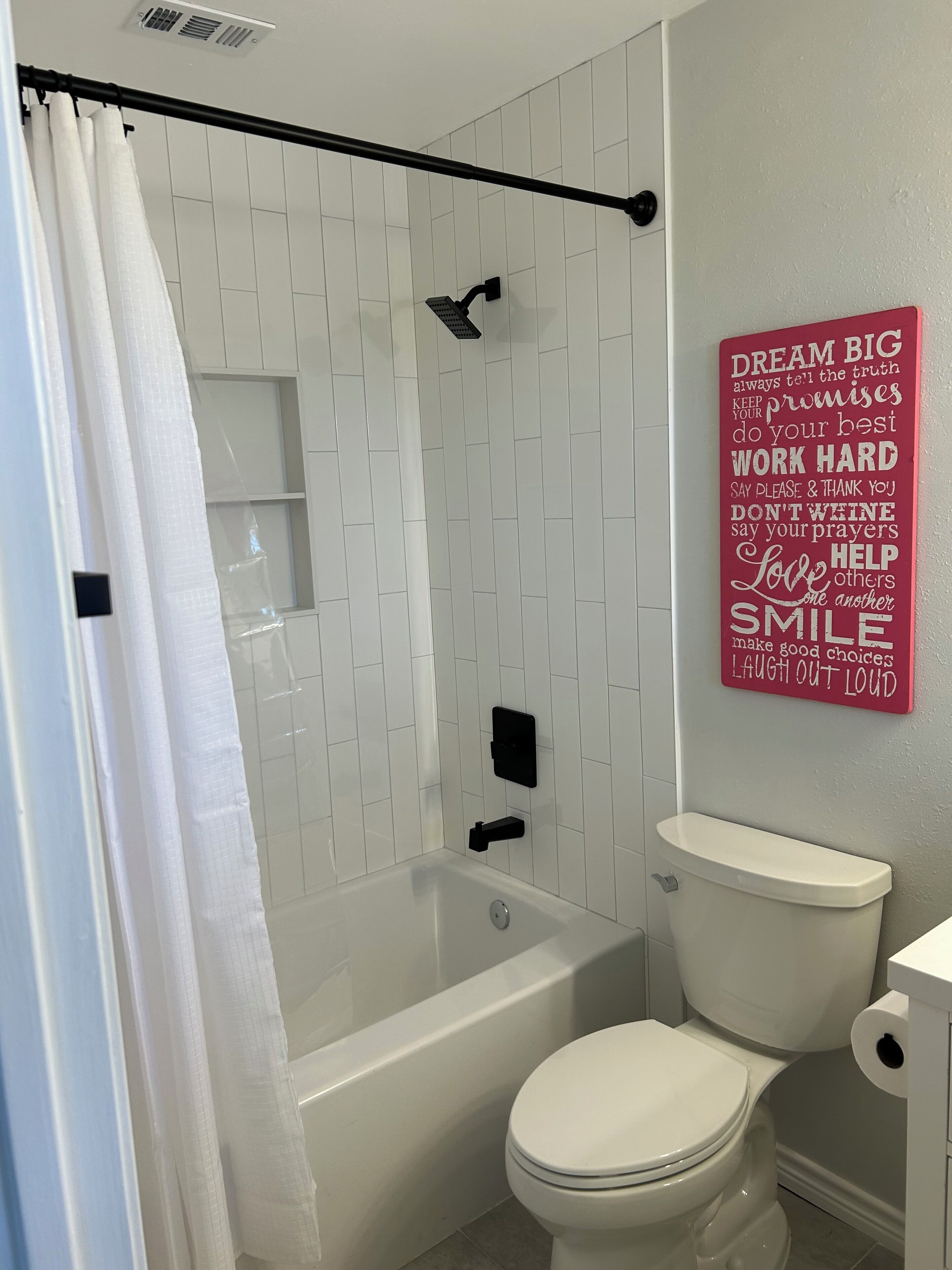 Une salle de bain avec douche, toilettes et une citation inspirante sur le mur.