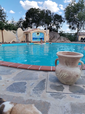 Relax by the pool surrounded by a mural of a beach scene.