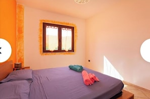 Relax in a spacious room with a large bed and a window with a decorative frame.