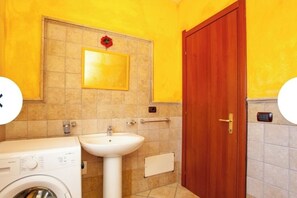 Bathroom features a sink, washing machine, and a mirror above the sink.