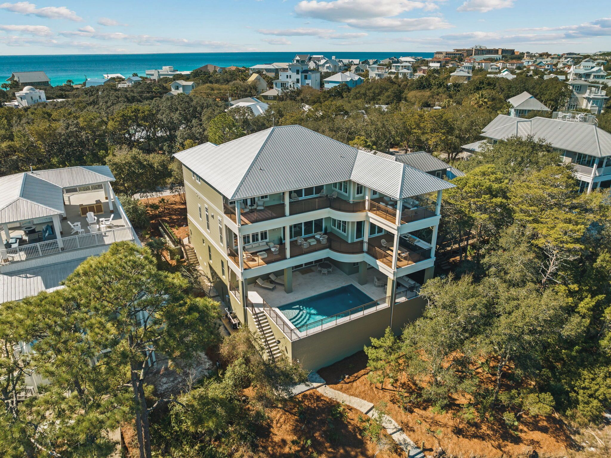 A multi-story beachfront property with a pool, balconies, and a view of the ocean.