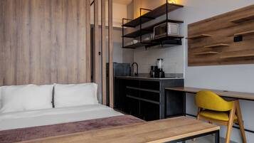 Un dormitorio moderno con cama, plataforma de madera y un espacio de escritorio con una silla.