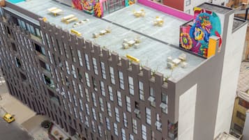 A multi-story building with a flat roof, multiple balconies, and a rooftop terrace with outdoor seating.