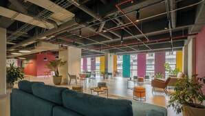 A spacious indoor area with a teal sofa, multiple seating options, and potted plants. - Ivin 567 by Atelier (Bogotá)