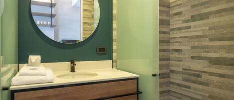 A bathroom with a round mirror, a sink with a towel, and a wooden vanity.
