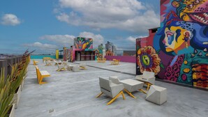 An outdoor seating area with concrete furniture and a colorful mural on the wall. - Ivin 567 by Atelier (Bogotá)