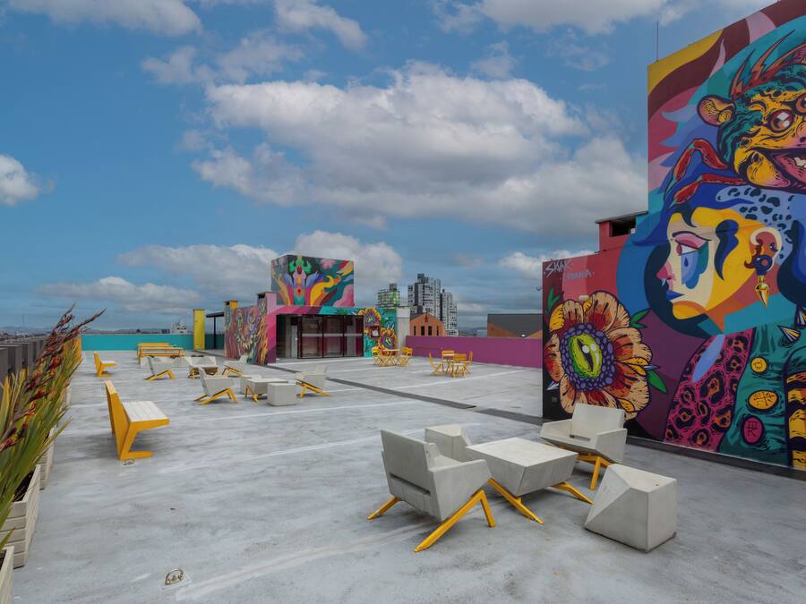 Un espace extérieur aménagé avec des meubles en béton et une fresque colorée sur le mur.