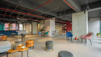 A spacious, modern lounge area with comfortable seating, a coffee table, and a large pillar.