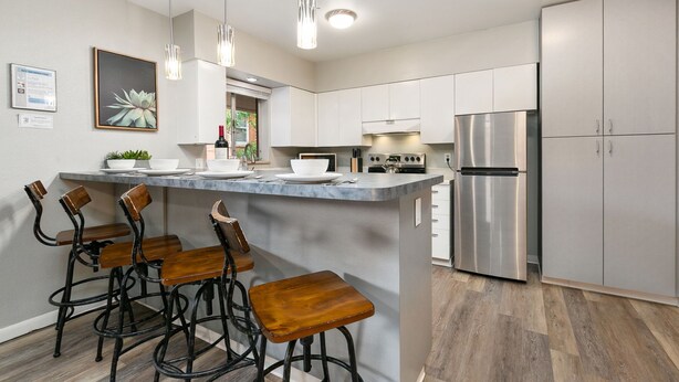 A modern kitchen with a central island, stainless steel appliances, and bar stools. - Peterson Flats - Downtown Group Retreat (Fort Collins)