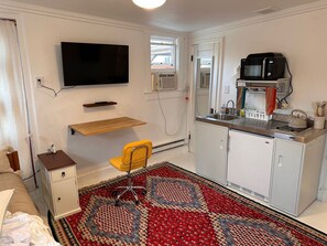 Compact room with a kitchenette, flat-screen TV, and a comfortable bed.