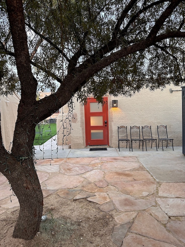 Guests enter through a stone-paved path to a welcoming entrance with a red door.