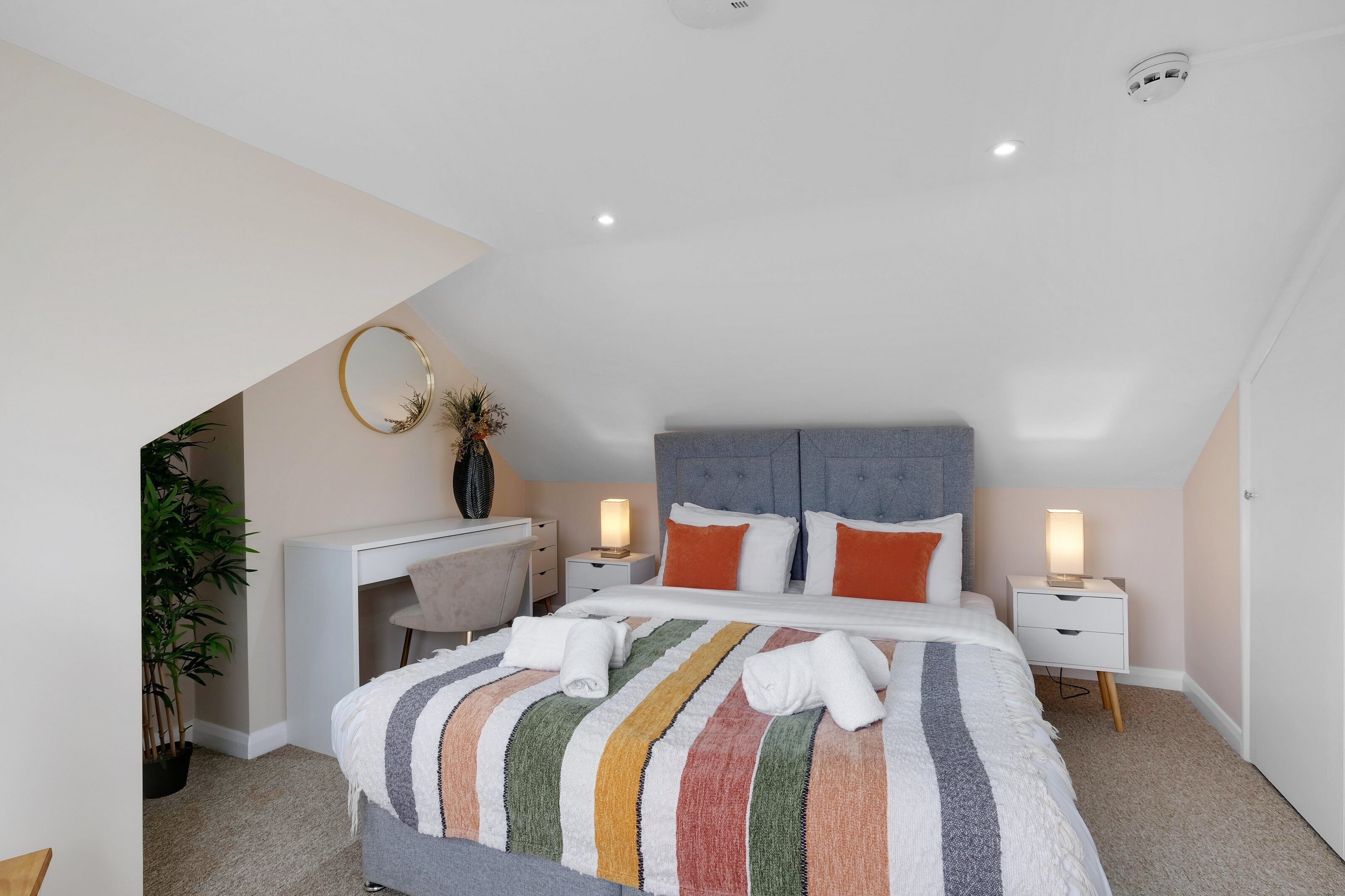 Un dormitorio moderno con una cama grande, un escritorio y una silla.