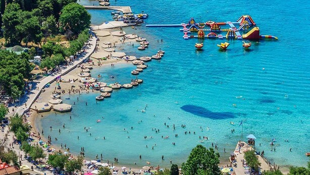 Eine Vogelperspektive einer Küstenregion mit Strand, Booten und einem Wasserpark.