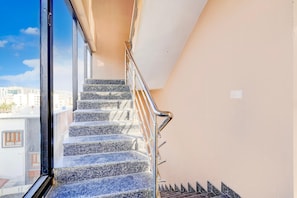 Eine Treppe mit Metallgeländern und Steinstufen, die zu einer oberen Etage führt.