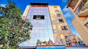 A hotel with a modern glass facade, a sign reading 'Collector,' and a colorful temple-like structure at the entrance. - Classic Bangalore Inn (Bengaluru)