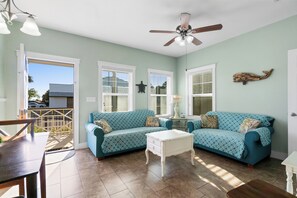 A living room with teal patterned sofas, a white coffee table, and a ceiling fan. - Cozy Cottage 1 of 4 with Bay Views| 2BR | Pool (Port St. Joe)