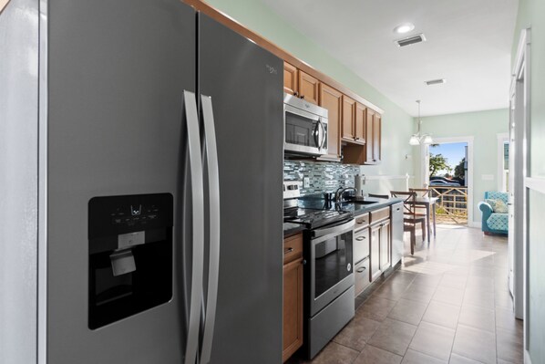 A modern kitchen with stainless steel appliances, wooden cabinets, and a tiled backsplash.