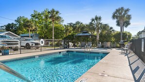A swimming pool with a 3 ft depth marker, surrounded by lounge chairs and a gazebo.