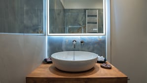 Une salle de bain avec un grand miroir, un lavabo rond blanc et un meuble-lavabo en bois.