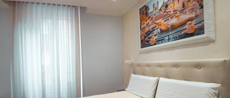 Una habitación de hotel con una cama grande, un cabecero con diseño capitonado y un cuadro de un paisaje urbano en la pared.