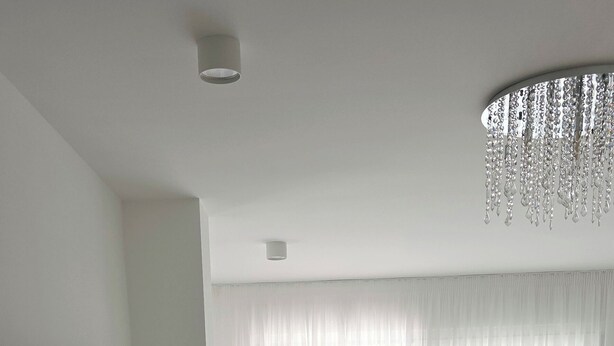 A modern, well-lit living room with a flat-screen TV, a white console table, a large window with sheer curtains, and a chandelier. - Holiday house in northern dalmatia (Zadar)