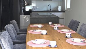 A modern dining area with a wooden table set for six, surrounded by grey upholstered chairs. - Holiday house in northern dalmatia (Zadar)