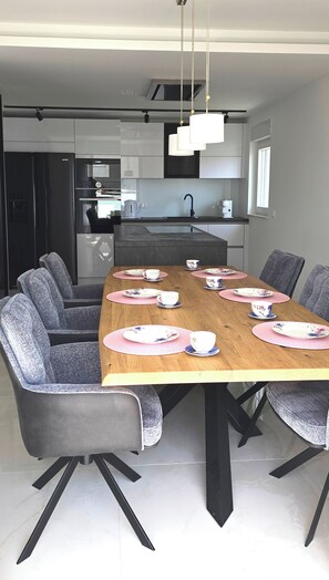 A modern dining area with a wooden table set for six, surrounded by grey upholstered chairs. - Holiday house in northern dalmatia (Zadar)