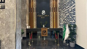 A reception area with a marble floor, a reception desk, and a wall with geometric patterns. -  Manazel Al Zaireen (Makkah)