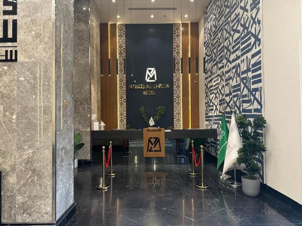 A reception area with a marble floor, a reception desk, and a wall with geometric patterns.