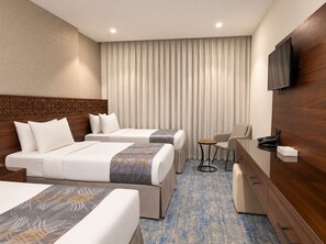 A hotel room with two beds, a desk, a chair, a television, and a large window with curtains. -  Manazel Al Zaireen (Makkah)