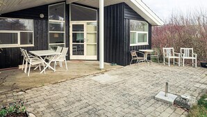 Et hus med overdækket terrasse, to vinduer og en dør.