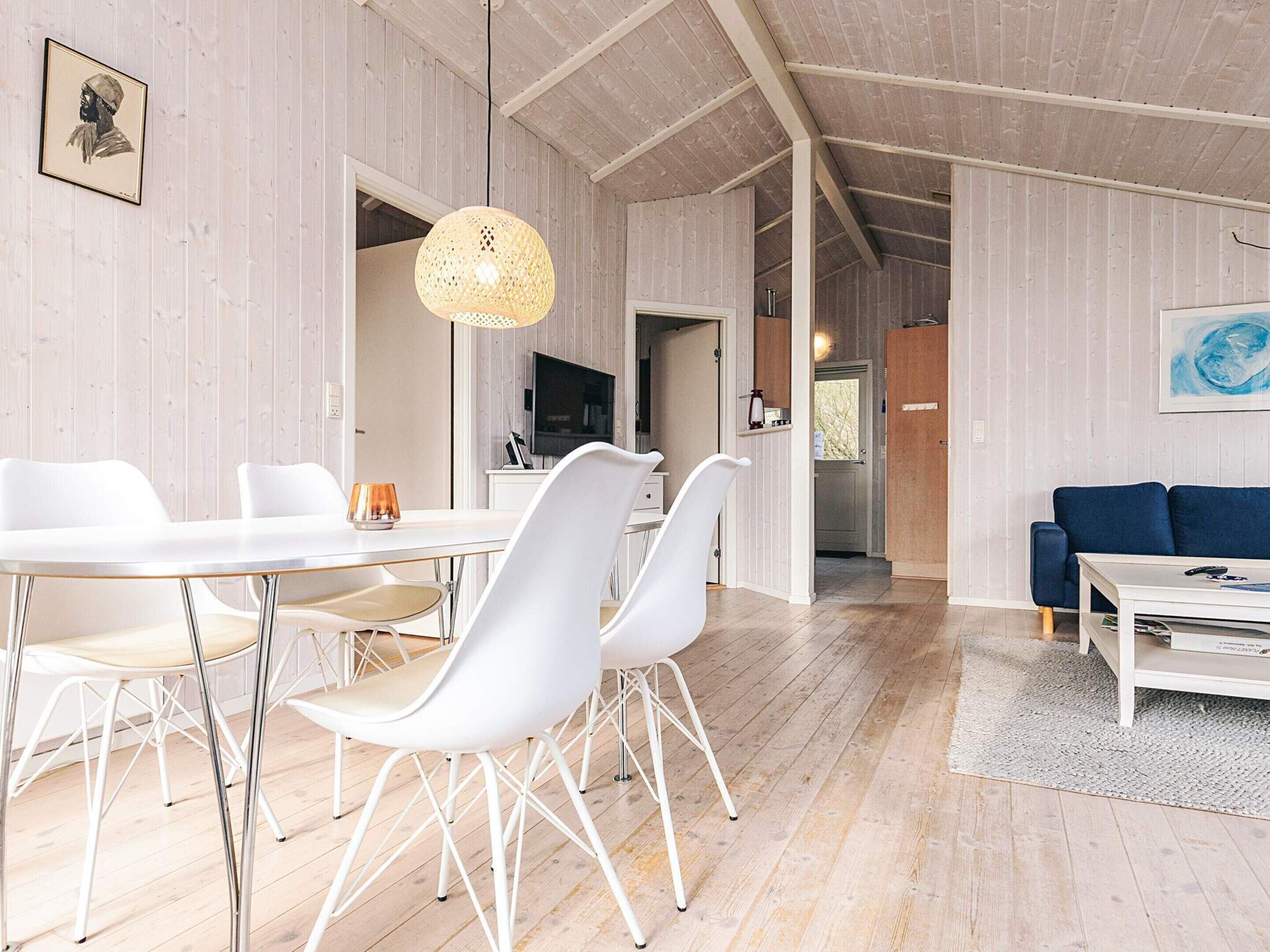 Uma sala de estar moderna com área de jantar, piso de madeira e televisão.