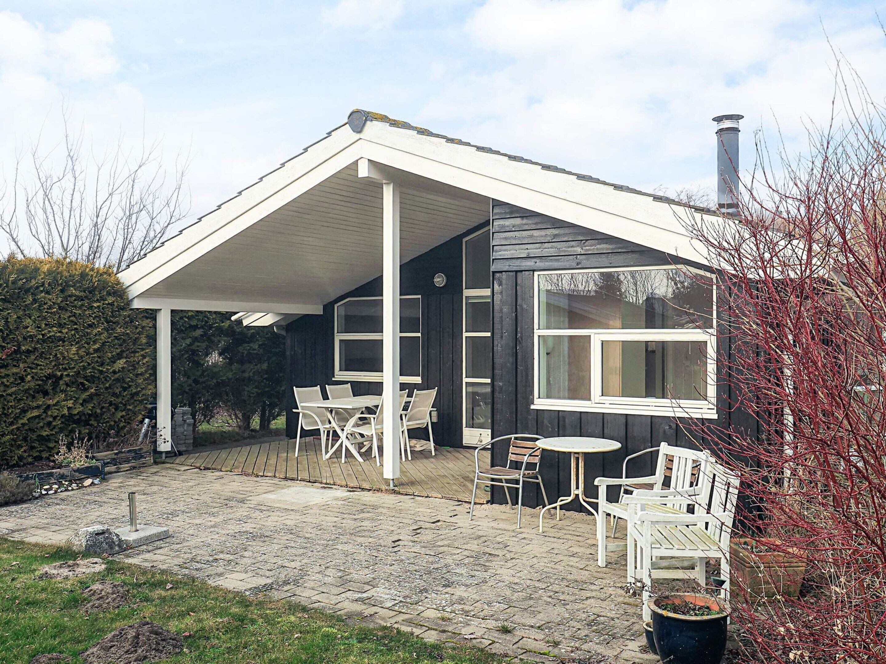 A house with a covered patio area, a chimney, and a garden with potted plants.