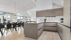 Una cocina moderna con una isla central, electrodomésticos integrados y un comedor con sillas y una mesa.