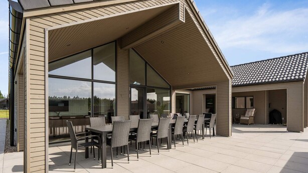 Un patio cubierto al aire libre con comedor, ventanas grandes y techo de baldosas.