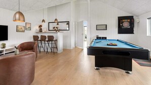 Ein modernes Wohnzimmer mit Billardtisch, Bar und Dartscheibe.