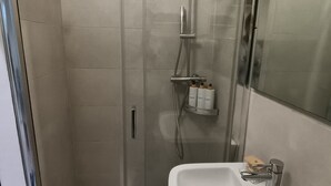 A modern bathroom with a glass-enclosed shower, a white sink, and a mirror. - Little house in Padua, close to the center and very convenient to the major concerts in Padua (Padova)