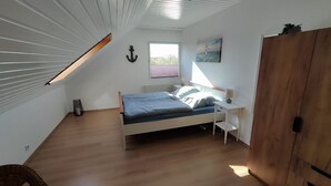 A bedroom with a bed, bedside table, lamp, and a window.