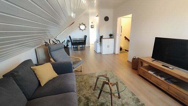 A modern living room with a grey sofa, a glass coffee table, and a TV on a wooden stand.
