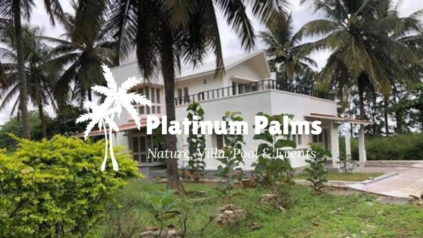 A modern villa with a pool and lush greenery, surrounded by palm trees.